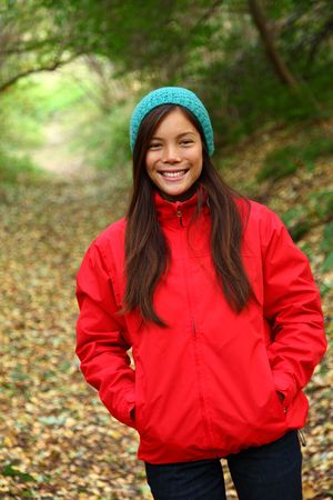 Autumn woman happy and smiling looking at camera during a walk in the forest during fallの写真素材