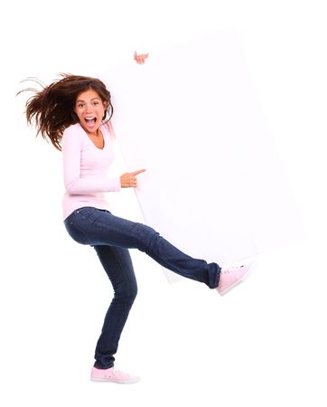 Excited woman holding sign. Funny and dynamic full length picture of woman holding a white blank billboard / placard. Beautiful mixed race asian / caucasian model. Isolated on white background.の写真素材