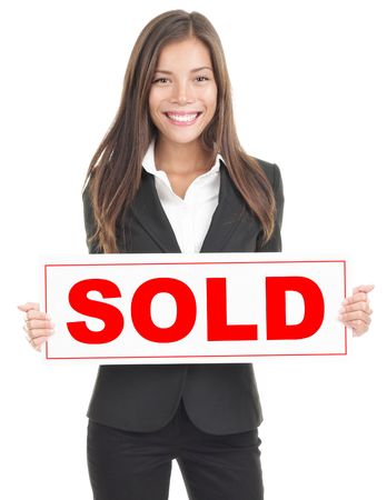 Real estate agent showing sold sign. Isolated on white background. Mixed asian / caucasian woman.の写真素材