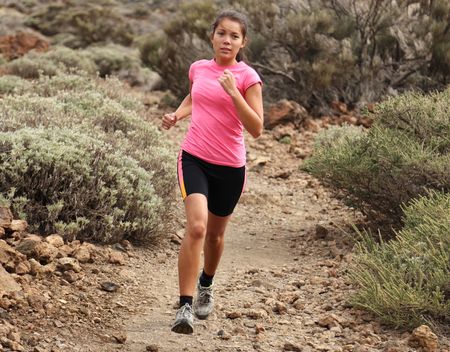 Woman running. Woman trail running outdoors on dirt single track in desert landscape in cross country running shoes.の写真素材