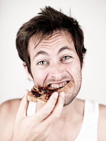 Man eating breakfast toast with peanut butter and jelly.の写真素材