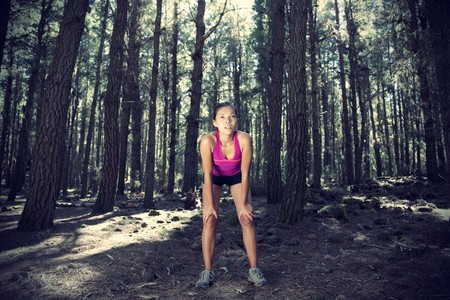 Woman running in forest. Female runner taking a break from running in beautiful forest with lots of mood / atmosphere and copy space. Beautiful young female athlete. の写真素材