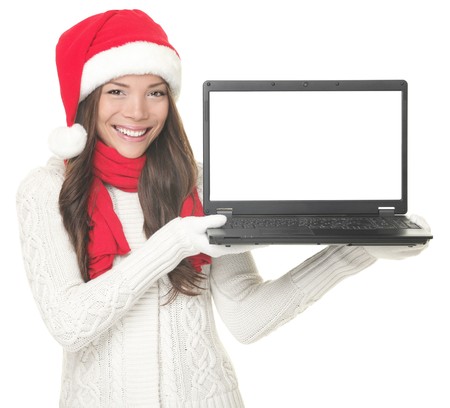  Laptop christmas girl. Smiling young woman in santa hat and sweater showing laptop. Copy space on computer screen. Caucasian Asian female model isolated on white background. の写真素材