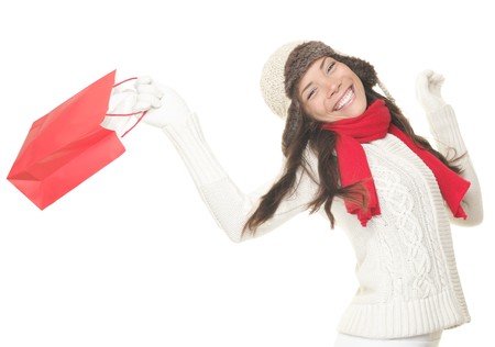 Christmas shopping woman with gift bag running joyful. Smiling young woman in winter clothes holding red shopping bags. Isolated on white background.の写真素材