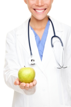 Doctor woman giving / showing apple. Young female medical professional isolated on white background.の写真素材