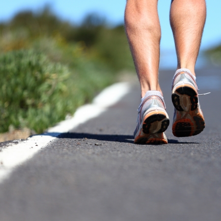 Running shoes on road - close up of runner legs, feet and running shoes with a lot of copy spaceの写真素材