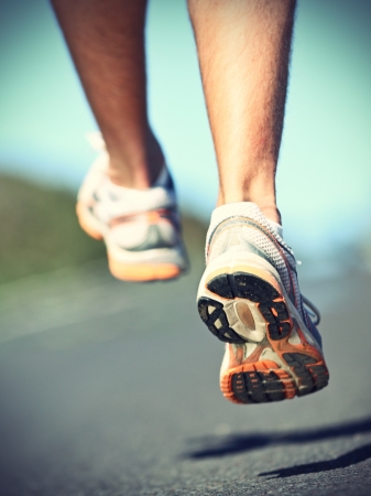 Running shoes on runner - closeup of sport shoes outdoors on man runner during run.の写真素材