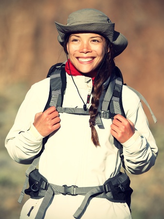 Hiker woman happy smiling outdoors while hiking in autumn or spring sporty outfit. Beautiful fresh Caucasian / Asian female model in warm evening light.の写真素材
