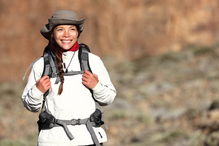 Hiking - woman hiker walking outdoors in mountain landscape smiling happy looking at copy space. Multiracial Asian Caucasian female model outdoors.の写真素材