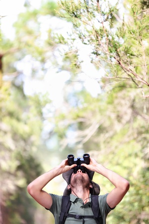 Binoculars - man hiker looking up at copy space during outdoors hiking trip の写真素材