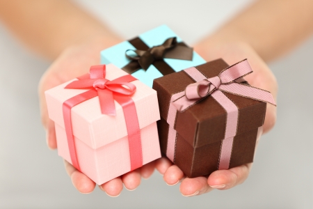 Cropped view image of a woman holding three colourful Christmas gifts with decorative ribbons and bows in the palms of her her hands, can also be used for anniversary, birthday or other celebrationの写真素材