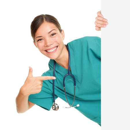 Medical sign person - woman showing blank poster billboard placard pointing. Young female nurse or medical doctor professional in green scrubs smiling happy isolated on white background.の写真素材