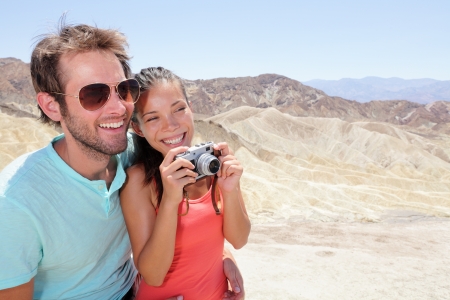 Tourists couple fun in Death Valley. Tourist woman and man taking pictures with camera enjoying the view and desert landscape of Zabriskie Point in Death Valley National Park, California, USA.の写真素材