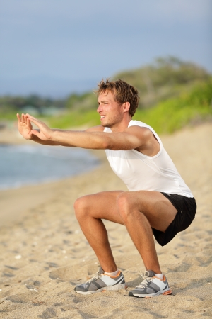 Fitness man training air squat exercise on beach outsideの写真素材