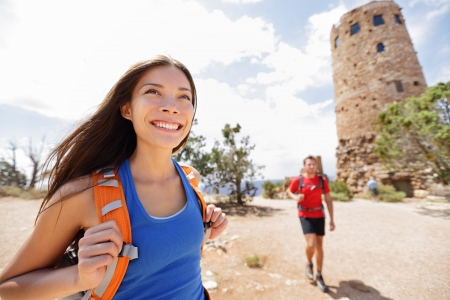 Hiking woman in grand canyon. Female hiker smiling happy with boyfriend in background during hike trekking at South Rim, Desert View Tower, Arizona, USA. Couple living healthy liifestyle.の写真素材