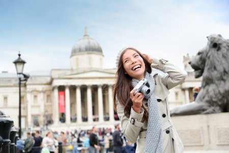 London tourist woman on Trafalgar Square in front of National Gallery taking photo holding camera smiling happy laughing having fun. Beautiful girl on travel vacation, London, England, United Kingdom.の写真素材