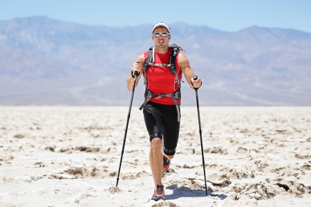 Ultra running man - trail runner in extreme race training for marathon. Fit male athlete running with trekking hiking poles in Death Valley, USA.の写真素材