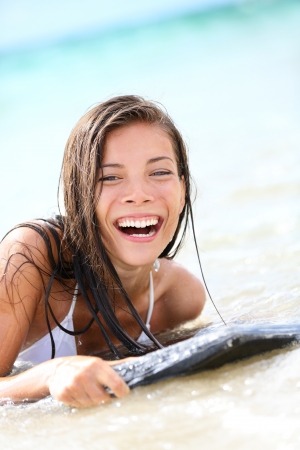 Surfboard laughing pretty mixed race, asian caucasian womanの写真素材