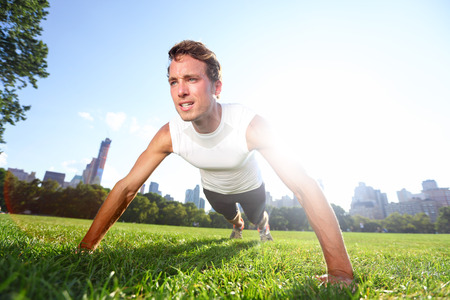 Push up man doing pushups in Central Park New York, Fitness male training push-ups outside on grass...