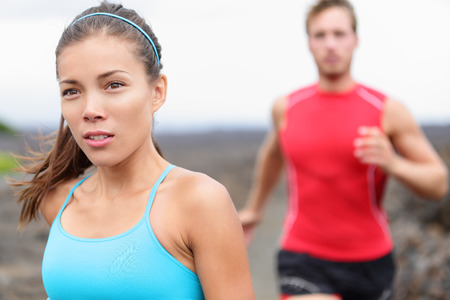 Close up of girl jogging outside with man in backgroundの写真素材
