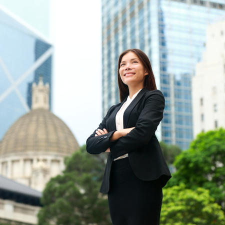 Businesswoman confident outside. Business woman standing proud and successful in suit cross-armed. Young multiracial Chinese Asian / Caucasian female professional in central Hong Kong.の写真素材