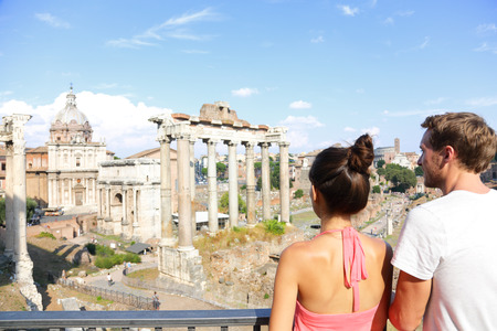 Roman Forum tourists looking at landmark in Rome sightseeing on travel vacation in Rome, Italy. Happy tourist couple, man and woman traveling on holidays in Europe smiling happy.の写真素材