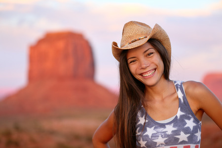 Cowgirl woman happy portrait in Monument Valley wearing cowboy hat. Beautiful smiling multiracial young woman outdoors, Arizona Utah, USA.の写真素材