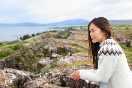 Iceland - woman in Icelandic sweater looking at Thingvellir place of Althing, the first parliament in the world. Girl at tourists destination sightseeing.の写真素材