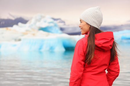 Woman at glacier lagoon on Iceland. Happy tourist woman looking enjoying view of Jokulsarlon glacial lake. Smiling woman in beautiful Icelandic nature landscape looking at iceberg.の写真素材