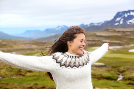 Happy free woman on Iceland in Icelandic sweater. Portrait of girl happy smiling outdoors in nature wearing Icelandic sweater. Pretty Asian Caucasian multiracial female modelの写真素材
