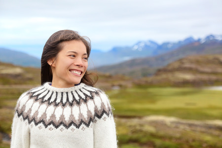 Woman on Iceland in Icelandic sweater. Portrait of girl happy smiling outdoors in nature wearing Icelandic sweater. Pretty Asian Caucasian multiracial female modelの写真素材