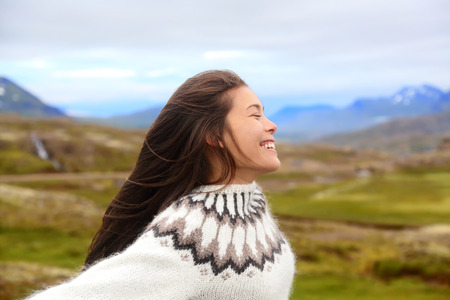 Free happy woman on Iceland in Icelandic sweater. Portrait of girl happy smiling outdoors in nature wearing Icelandic sweater. Pretty Asian Caucasian multiracial female modelの写真素材