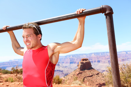 Exercising Fitness athlete man training pull ups in amazing nature landscape of Grand Canyon....