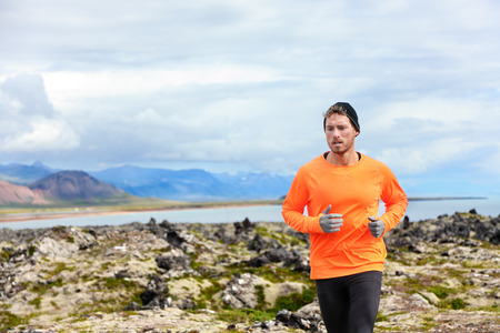 Sport running man in cross country trail run. Male runner exercising and training outdoors in...