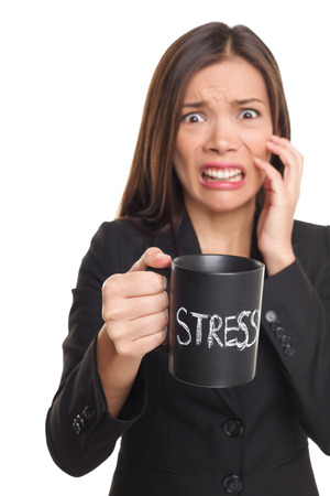Stress concept. Business woman stressed being too busy. Businesswoman in suit holding head drinking coffee creating more stress. Mixed race Asian Caucasian female isolated on white background.の写真素材