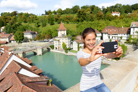 Travel selfie smart phone by woman in Bern Switzerland, Europe. Happy smiling multiracial Asian girl...