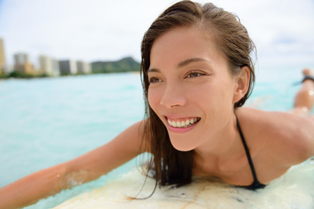 Surfer girl surfing on Waikiki Beach, Oahu, Hawaii. Female bikini woman on surfboard smiling happy living healthy active lifestyle on Hawaiian beach. Asian Caucasian model.の写真素材