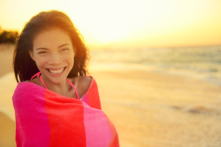 Young pretty mixed race Asian Caucasian model woman wrapped in towel standing in beach sunset. Smiling happy enjoying summer holiday travel vacation. Hawaii.の写真素材