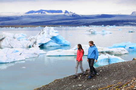 People hiking on Iceland Jokulsarlon glacial lagoon / glacier lake. Active lifestyle couple tourists walking enjoying beautiful Icelandic nature landscape with Vatnajokull in backround.の写真素材