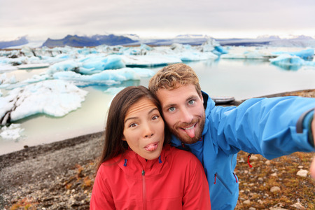 Funny selfie couple taking self portrait photograph on Iceland having fun on travel by Jokulsarlon glacial lagoon / glacier lake. Tourists enjoying beautiful Icelandic nature landscape Vatnajokull.の写真素材