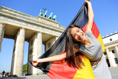 German flag - Woman happy at Berlin, Germany, Brandenburg Gate cheering celebrating waving flag by Brandenburger Tor. Cheerful excited multiracial woman in Germany travel concept.の写真素材