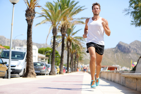 Fit male runner running outside on boardwalk. Young man model training fitness jogging on Mallorca...
