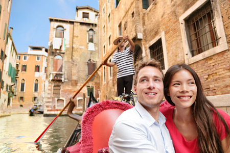 Romantic travel couple in Venice on Gondola ride romance in boat talking happy together on travel vacation holidays. の写真素材