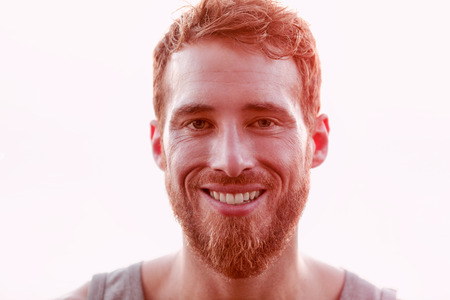 Happy young man isolated against white background. Portrait of male is with beards. Closeup of handsome man smiling.の写真素材