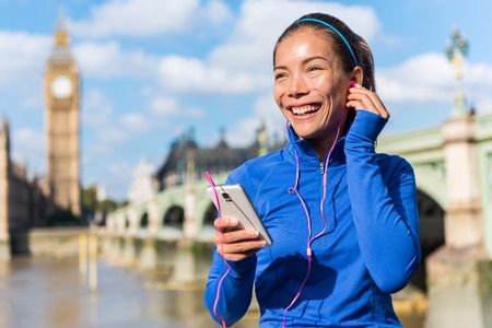London running lifestyle woman listening to fitness music playlist on smart phone. Female going for...