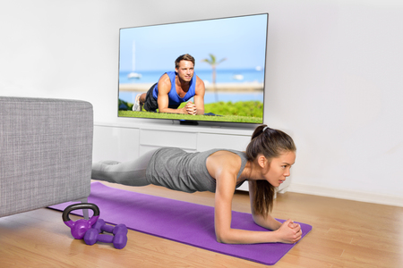 Living room fitness workout - girl doing plank exercises to exercise core at home. Young Asian woman training muscles in front of the TV as part of a healthy lifestyle without going to the gym.の写真素材
