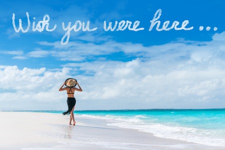 Wish you were here cloud message written in sky above woman walking on beach vacation Luxury travel Caribbean destination. Tourist relaxing on summer holiday at resort. Popular saying postcard.の写真素材
