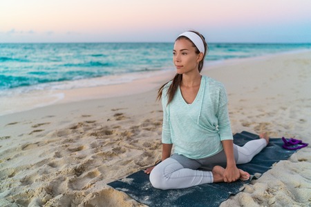 Yoga mat woman stretching hip, hamstring muscles and groin area, leg muscles with pigeon pose...