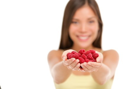 Woman holding fresh raspberries in hands closeup isolated on white background. Asian woman showing...