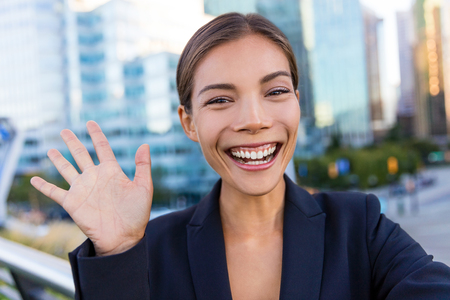 Business woman taking selfie photo using smart phone app on smartphone for social media. Young businesswoman using smartphone smiling happy wearing suit jacket outdoors. Urban female professional.の写真素材